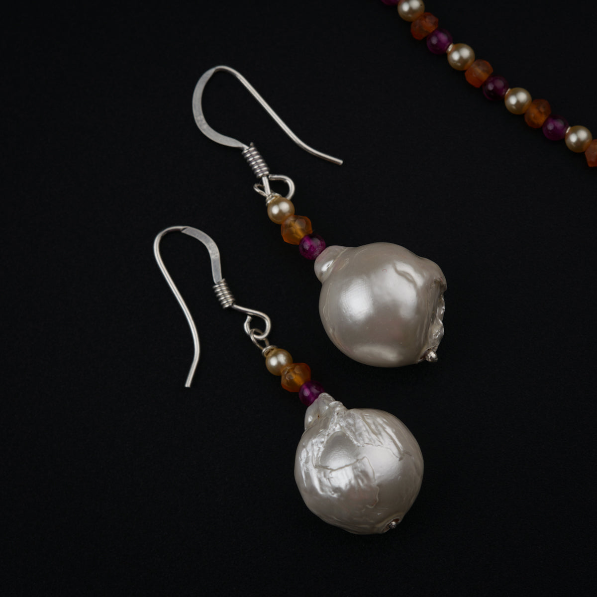 a pair of earrings with pearls and beads