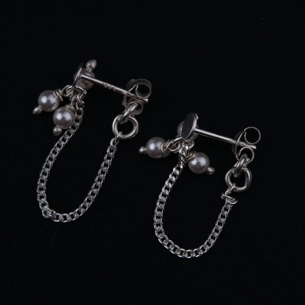a pair of earrings with chains and pearls
