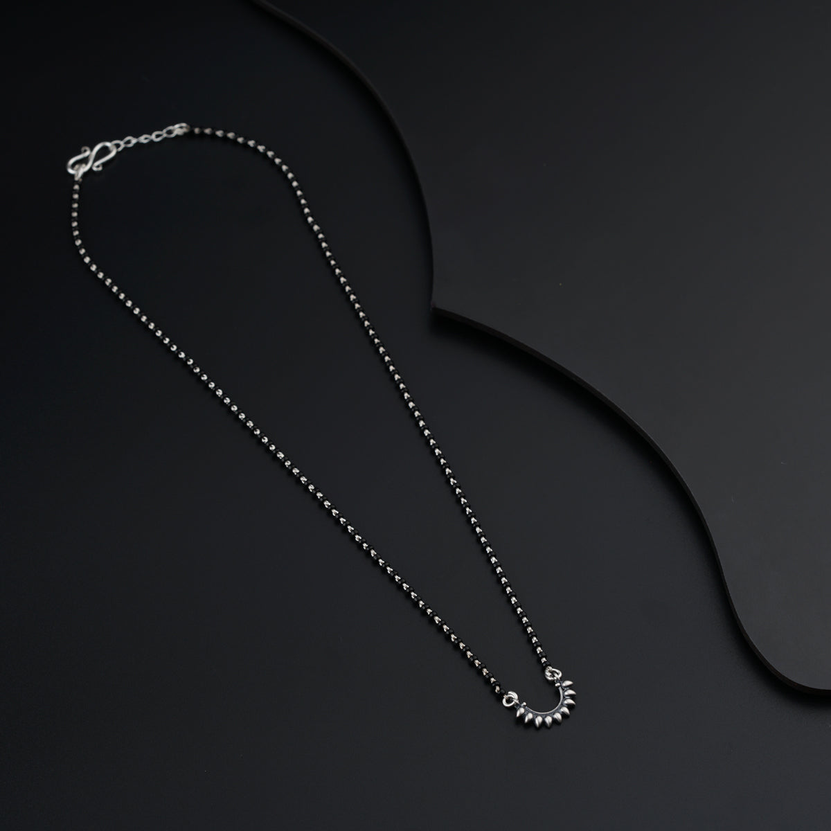 a necklace with a heart on it on a black surface