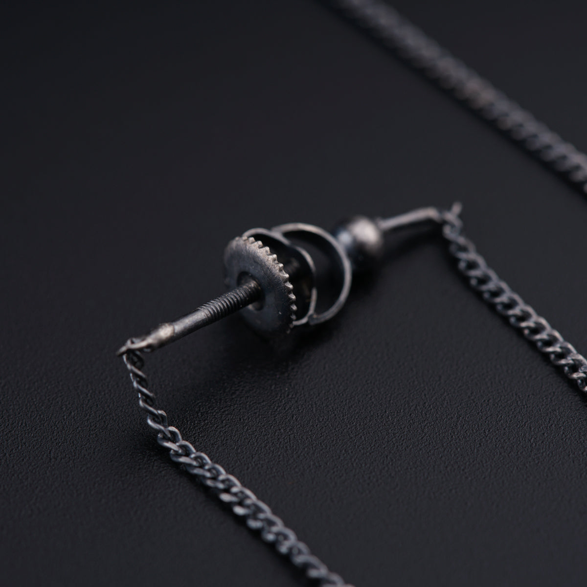 a pair of screws and a chain on a black surface