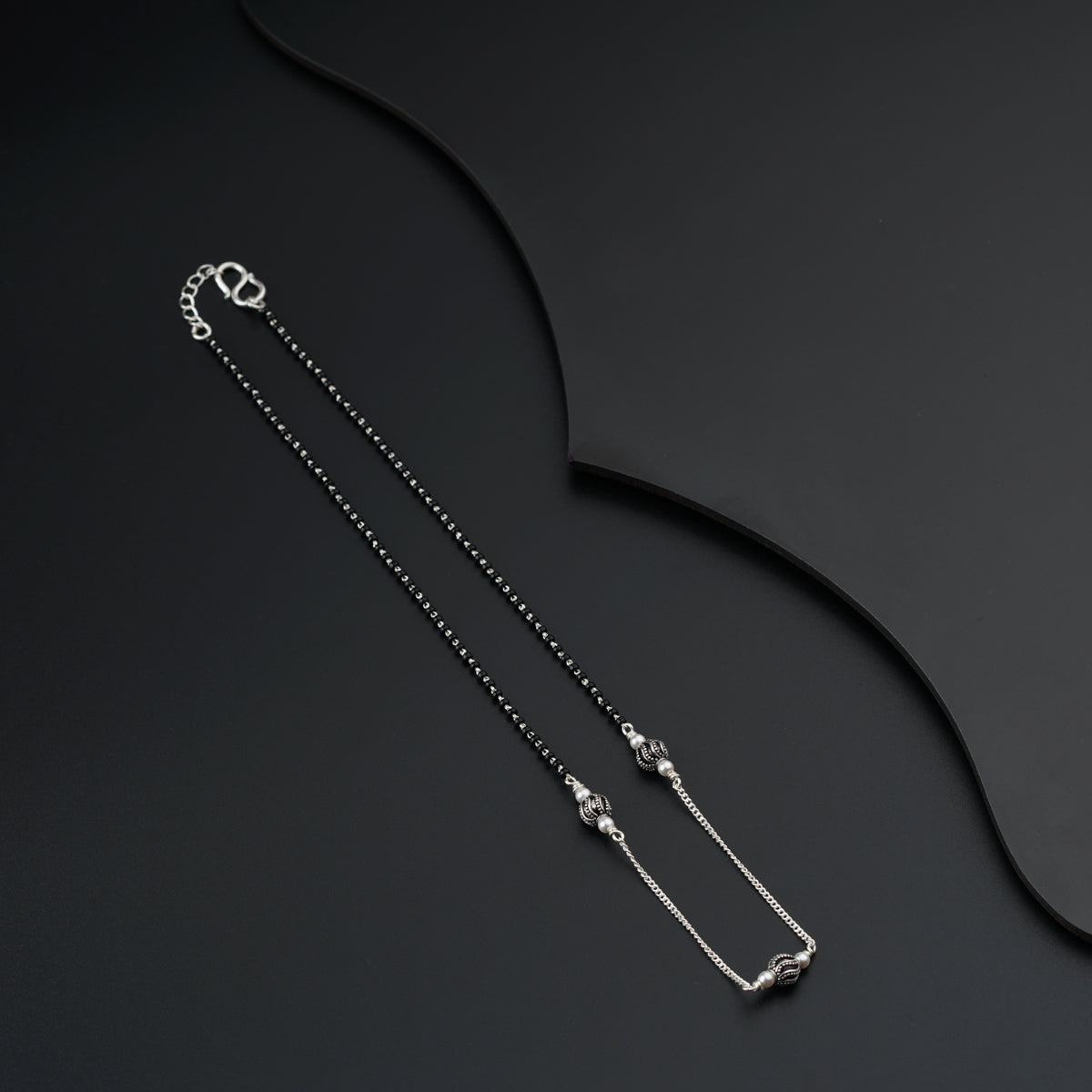 a necklace with a long chain and a clasp on a black background