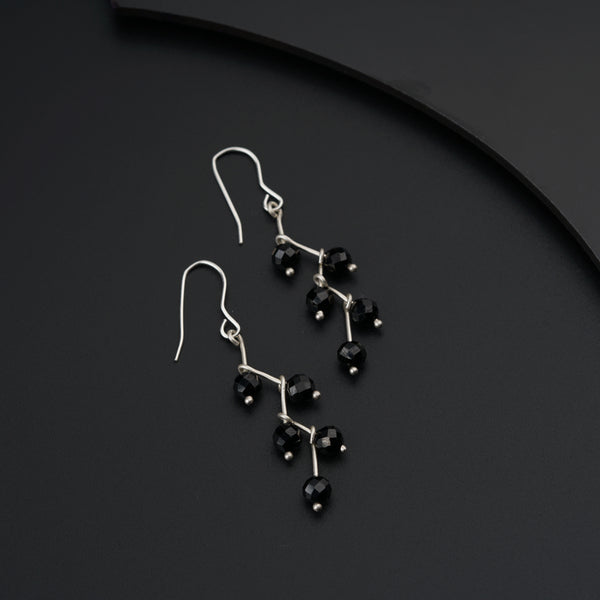 a pair of black beaded earrings sitting on top of a table