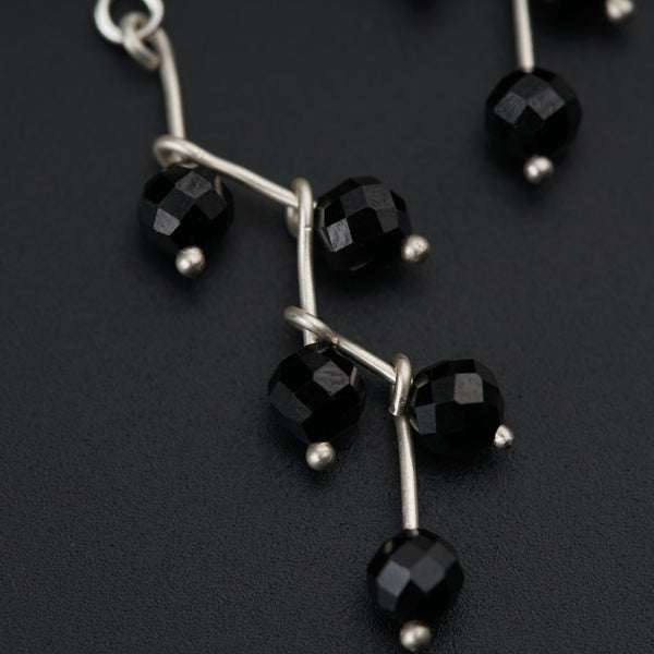 a pair of black glass beaded earrings on a black surface