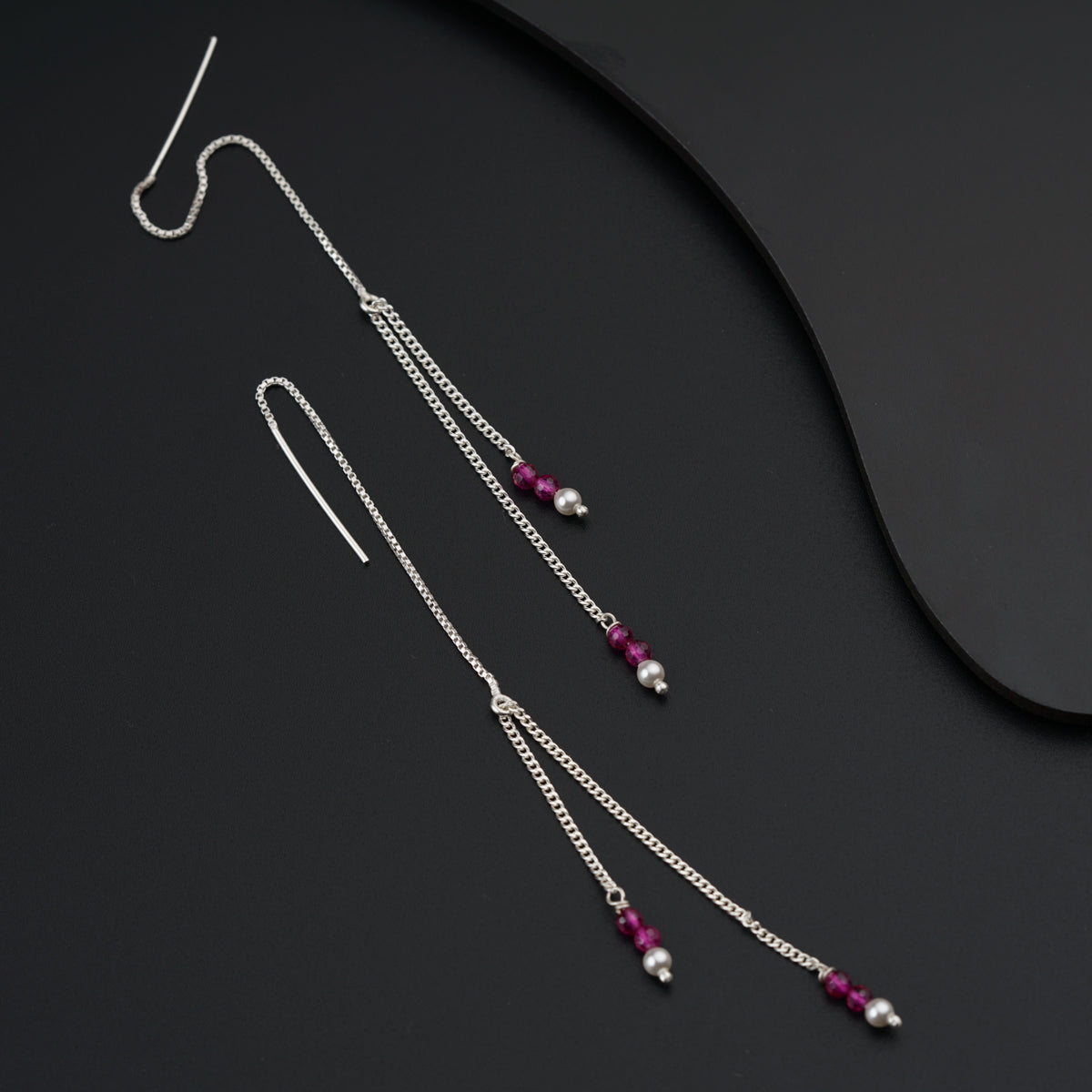 a pair of long silver chain earrings with red beads