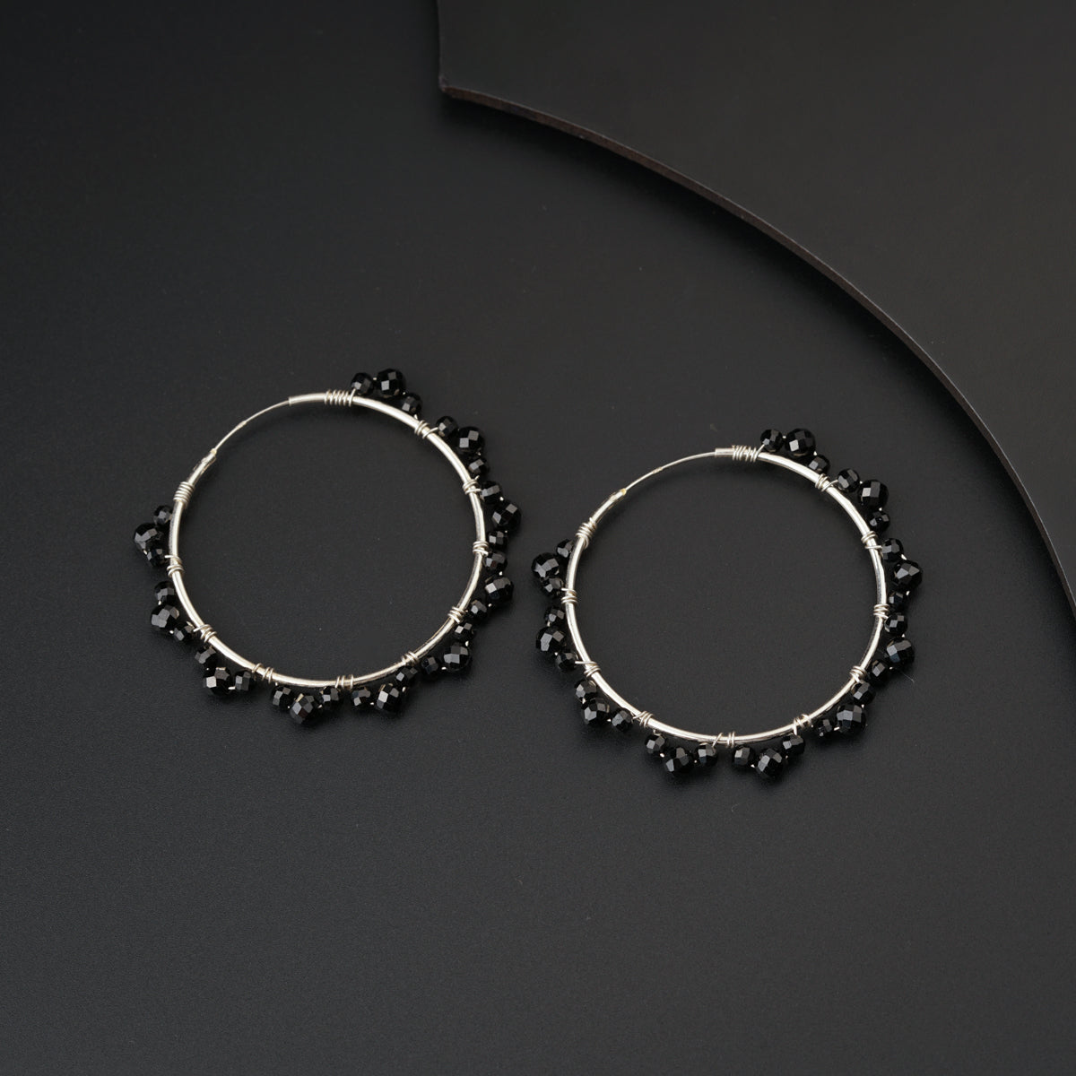 a pair of black beaded hoop earrings