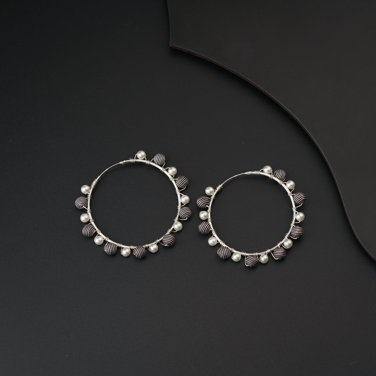 a pair of silver hoop earrings on a black surface