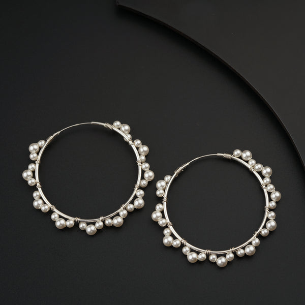 a pair of silver hoop earrings with pearls