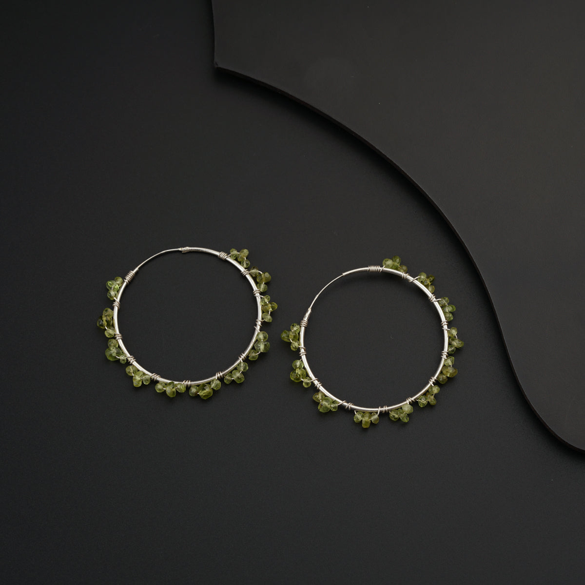 a pair of hoop earrings with green beads