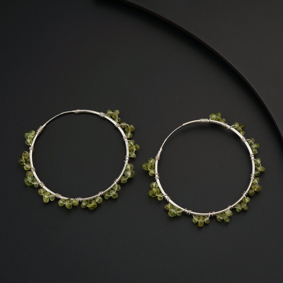 a pair of silver hoop earrings with green beads