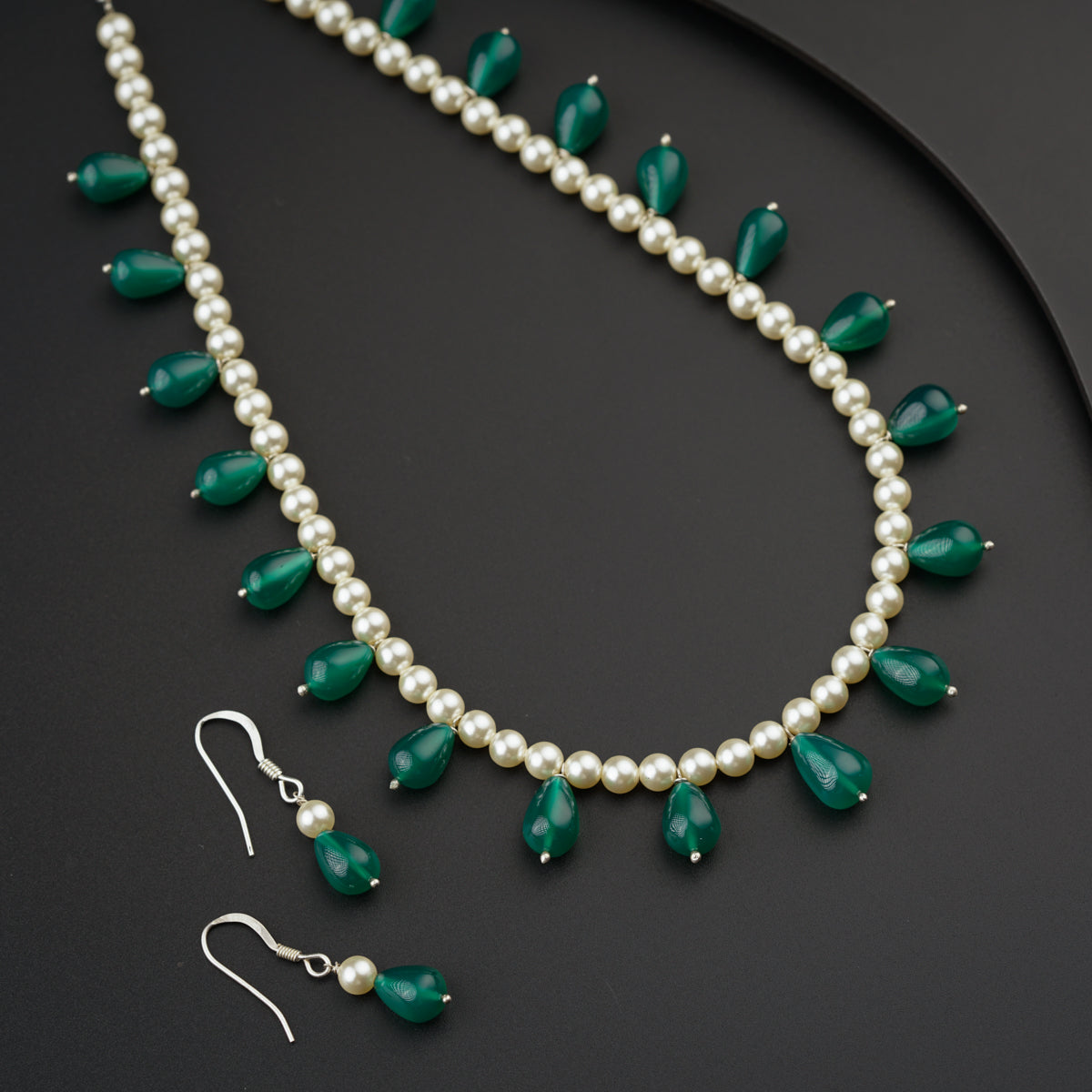 a necklace and earring set with pearls and green stones