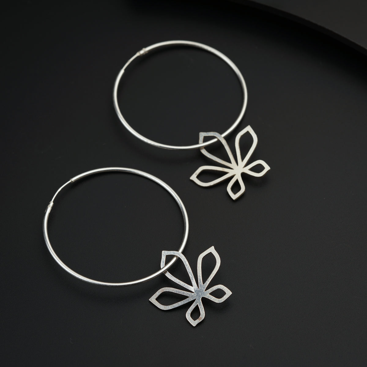 a pair of silver hoop earrings with a flower design