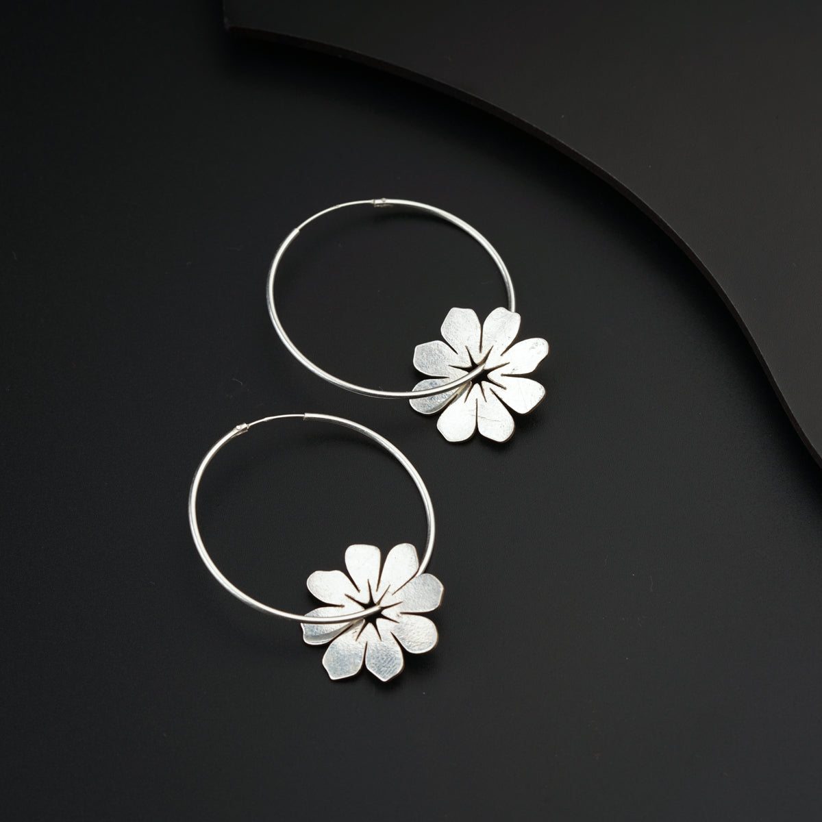 a pair of flower hoop earrings on a black surface