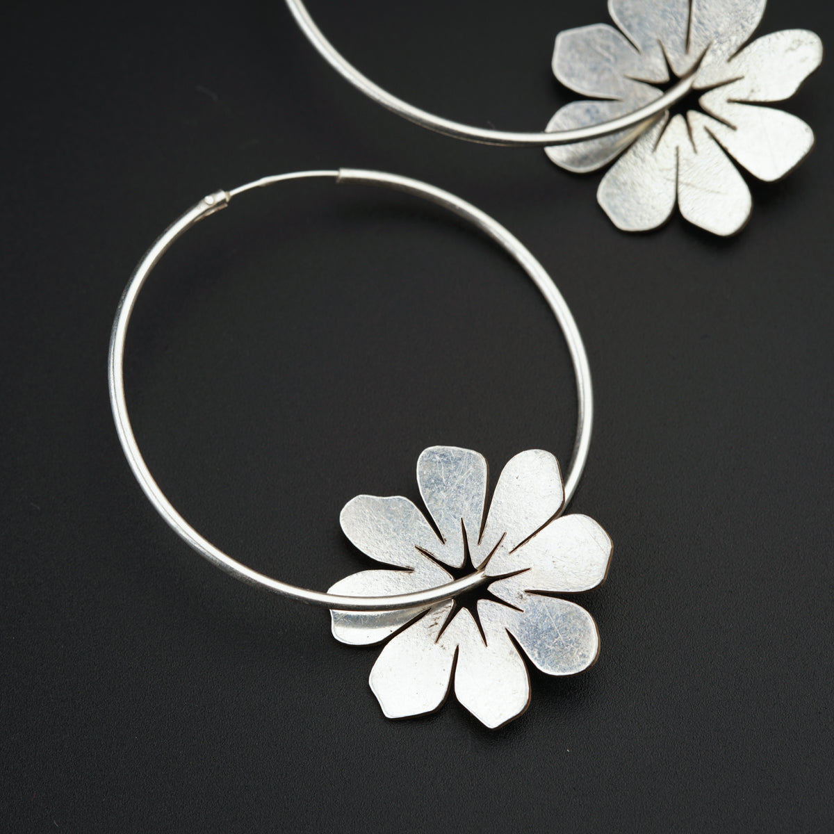 a pair of silver hoop earrings with flowers on them