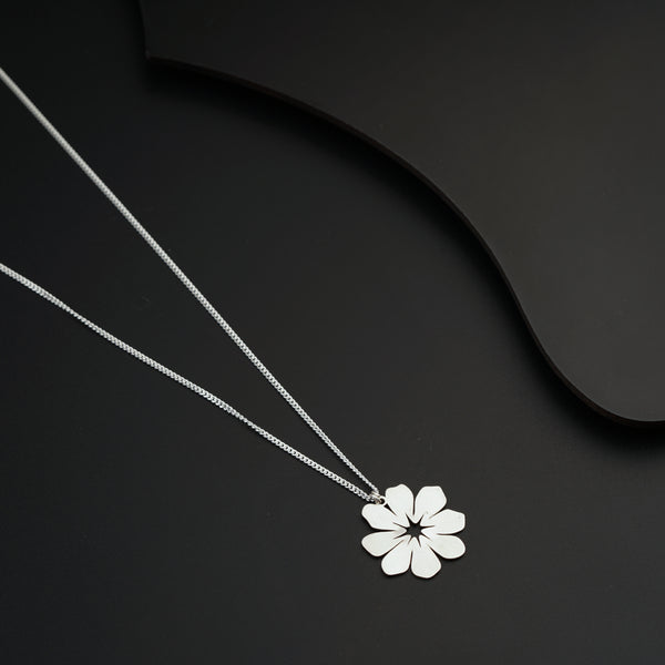 a necklace with a flower on a black background