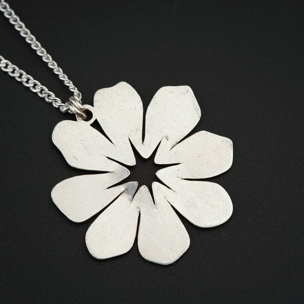 a silver necklace with a flower on a chain