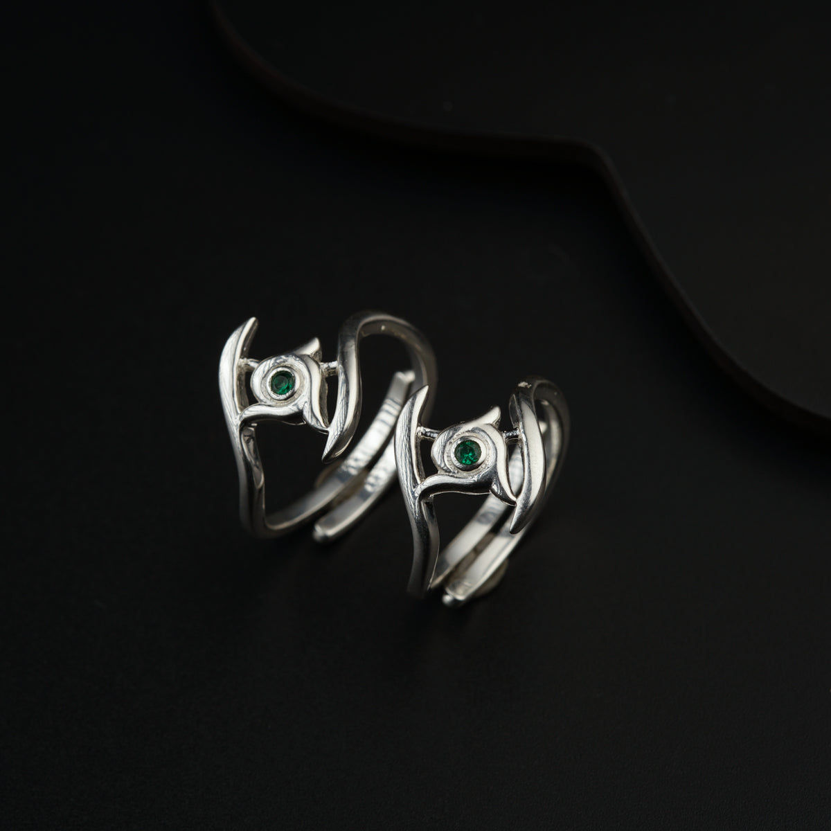 a pair of silver rings with green eyes