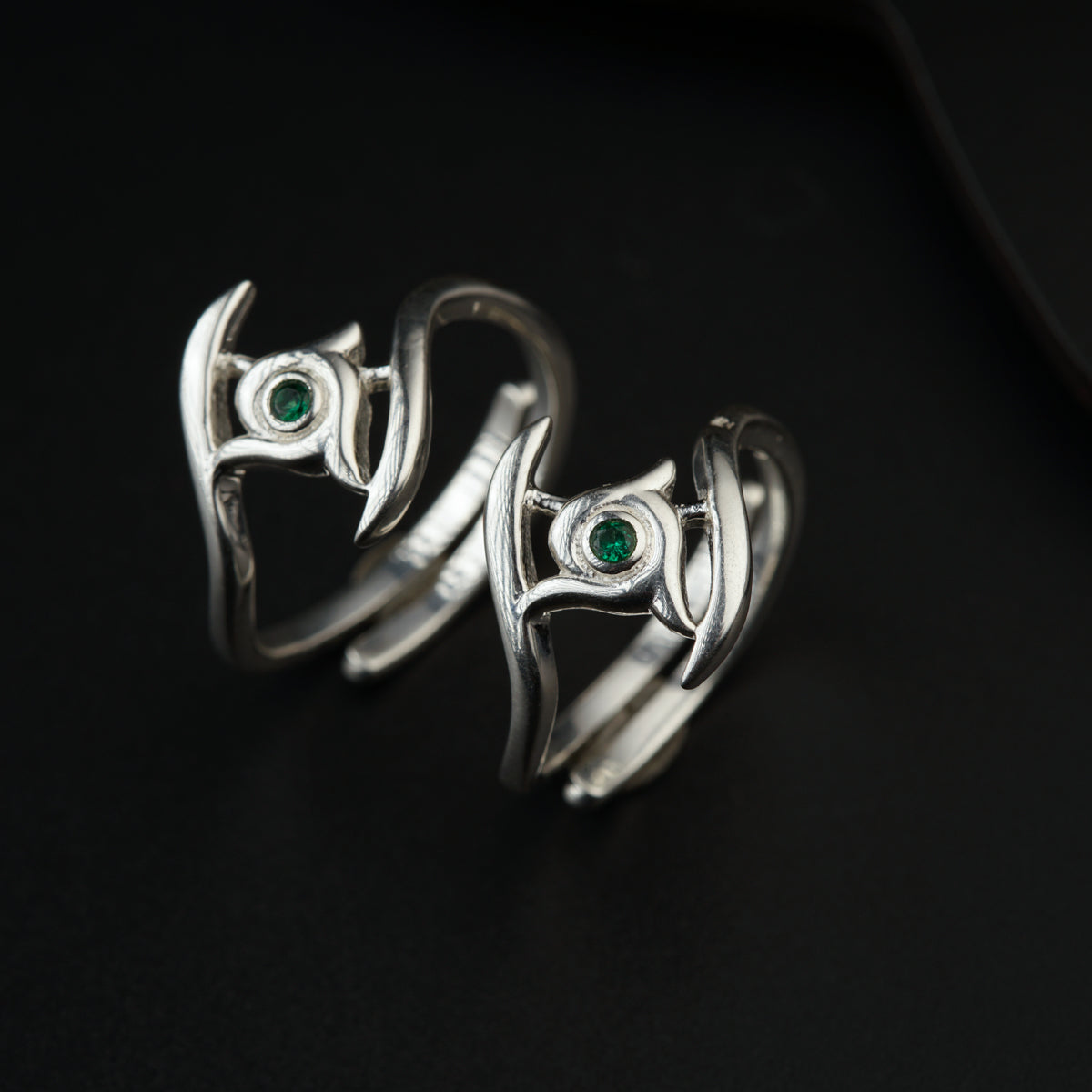 a pair of silver rings with green stones