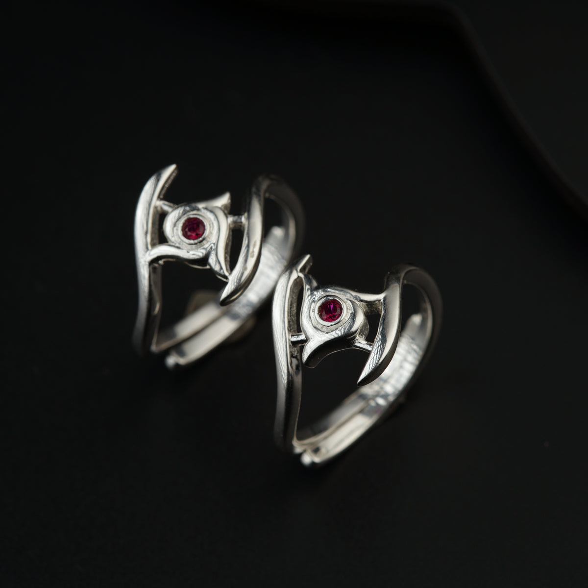 a pair of silver rings with red stones