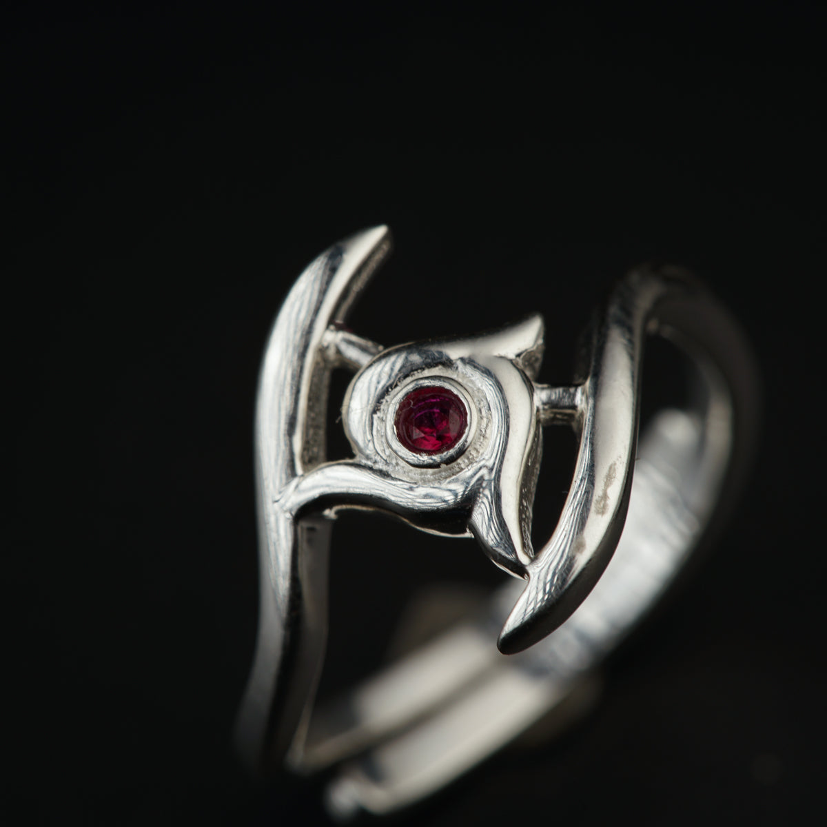 a close up of a silver ring with a red stone
