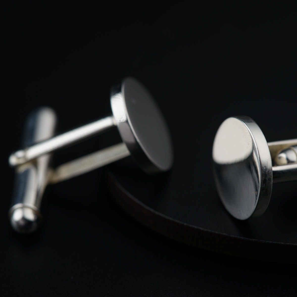a pair of silver cufflinks on a black surface