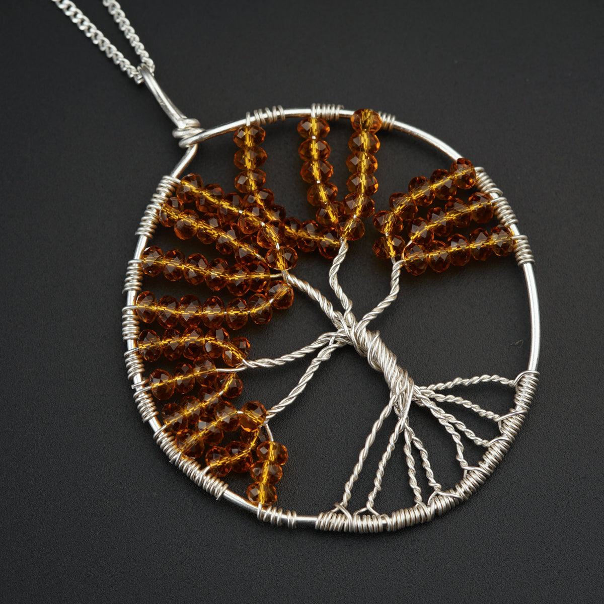 a wire and glass tree of life pendant on a chain