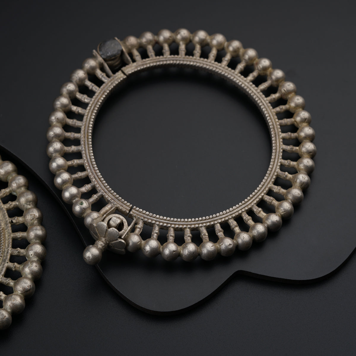 a pair of silver bracelets on a black surface