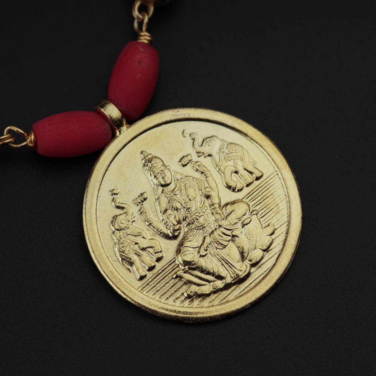 a red beaded necklace with a gold coin on it