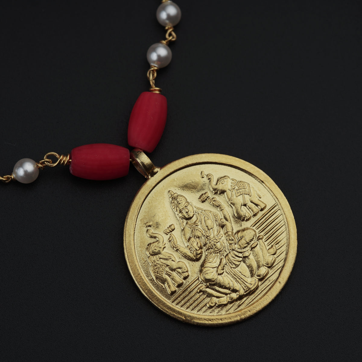 a red beaded necklace with a gold coin on it