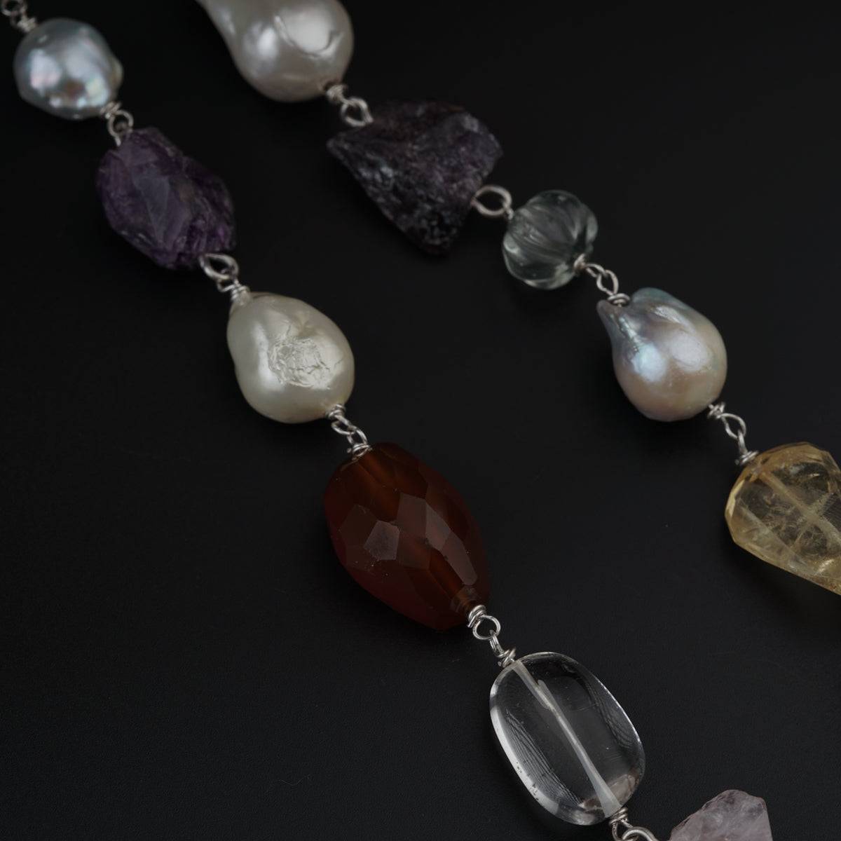a long necklace with different colored stones and pearls