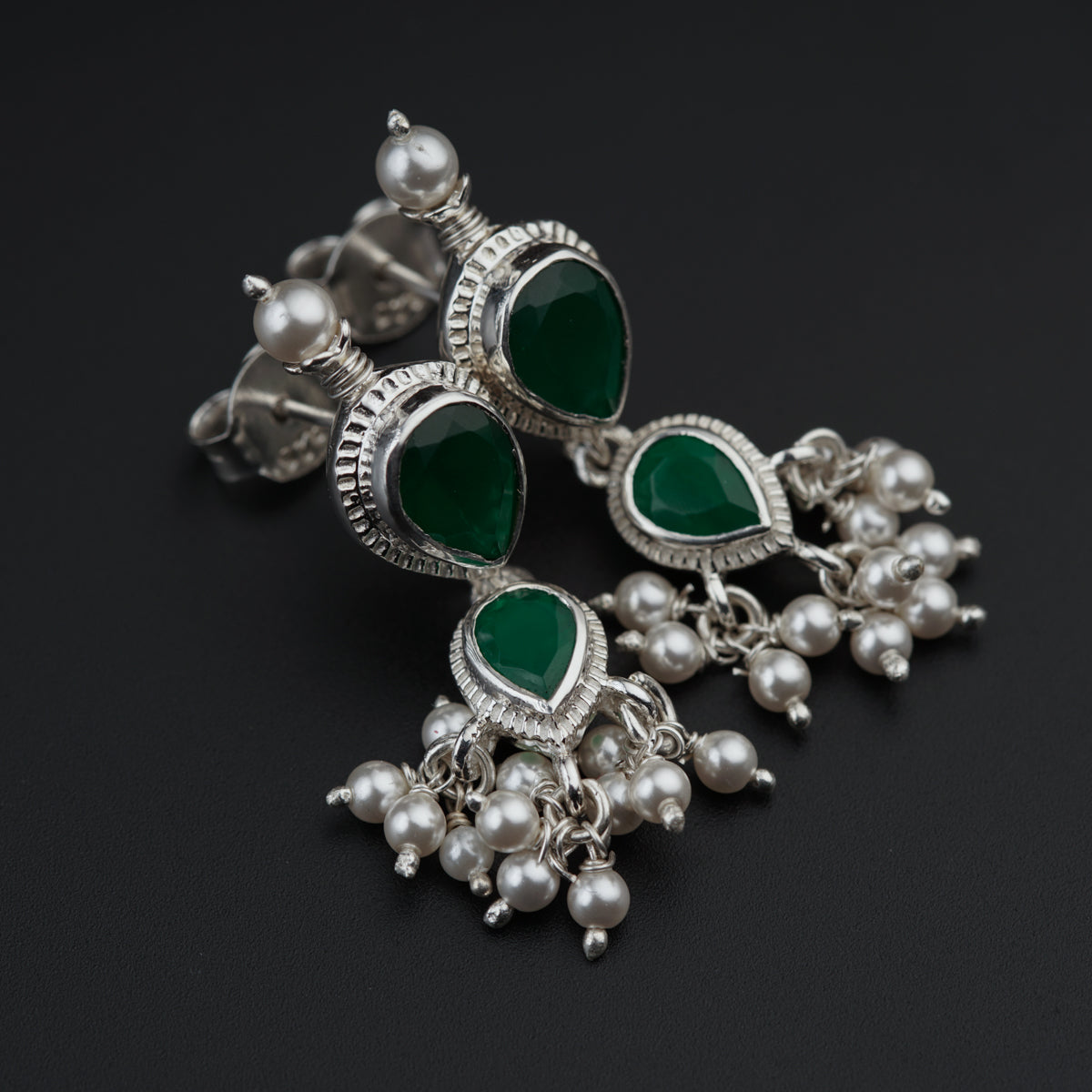 a pair of earrings with green stones and pearls
