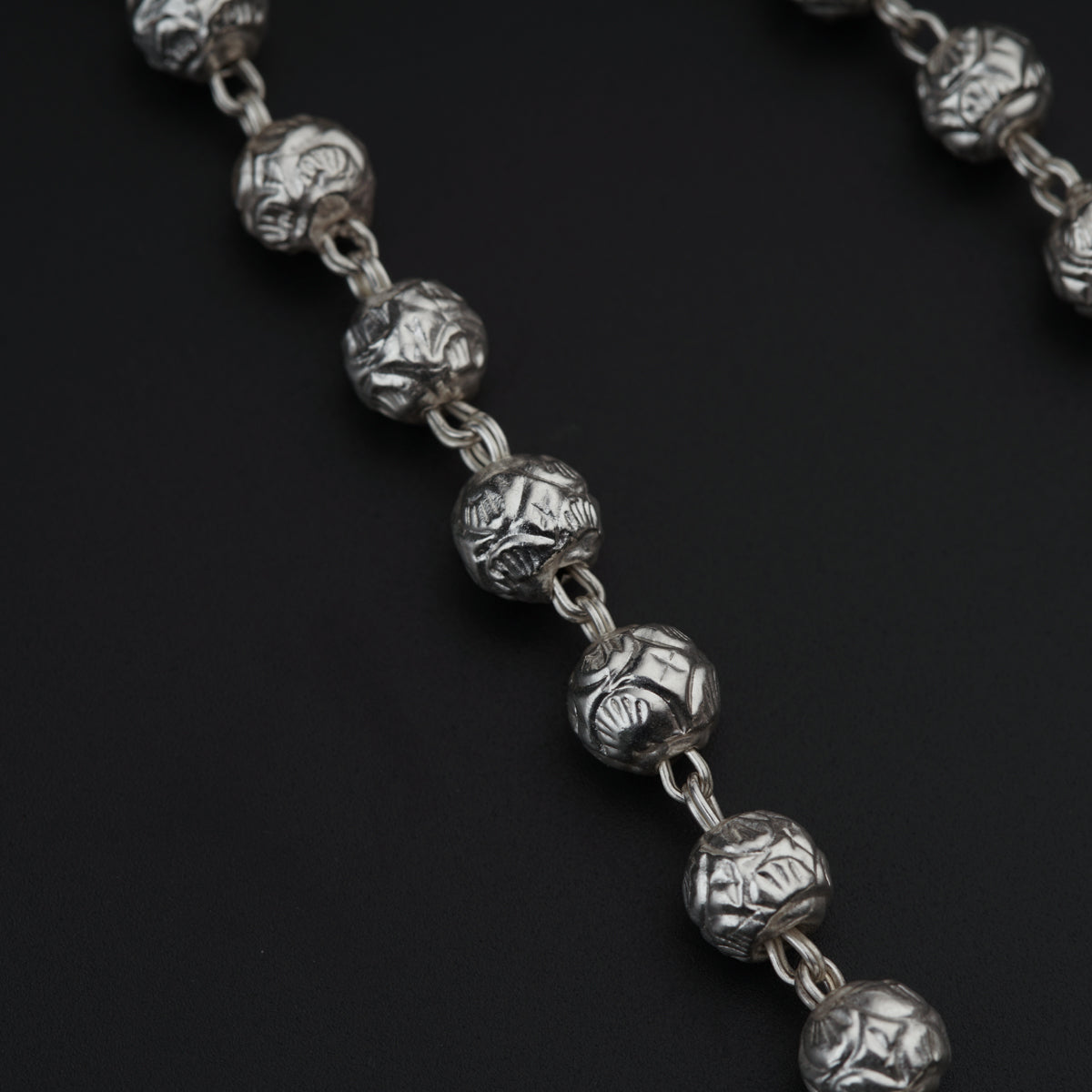 a close up of a silver chain on a black surface