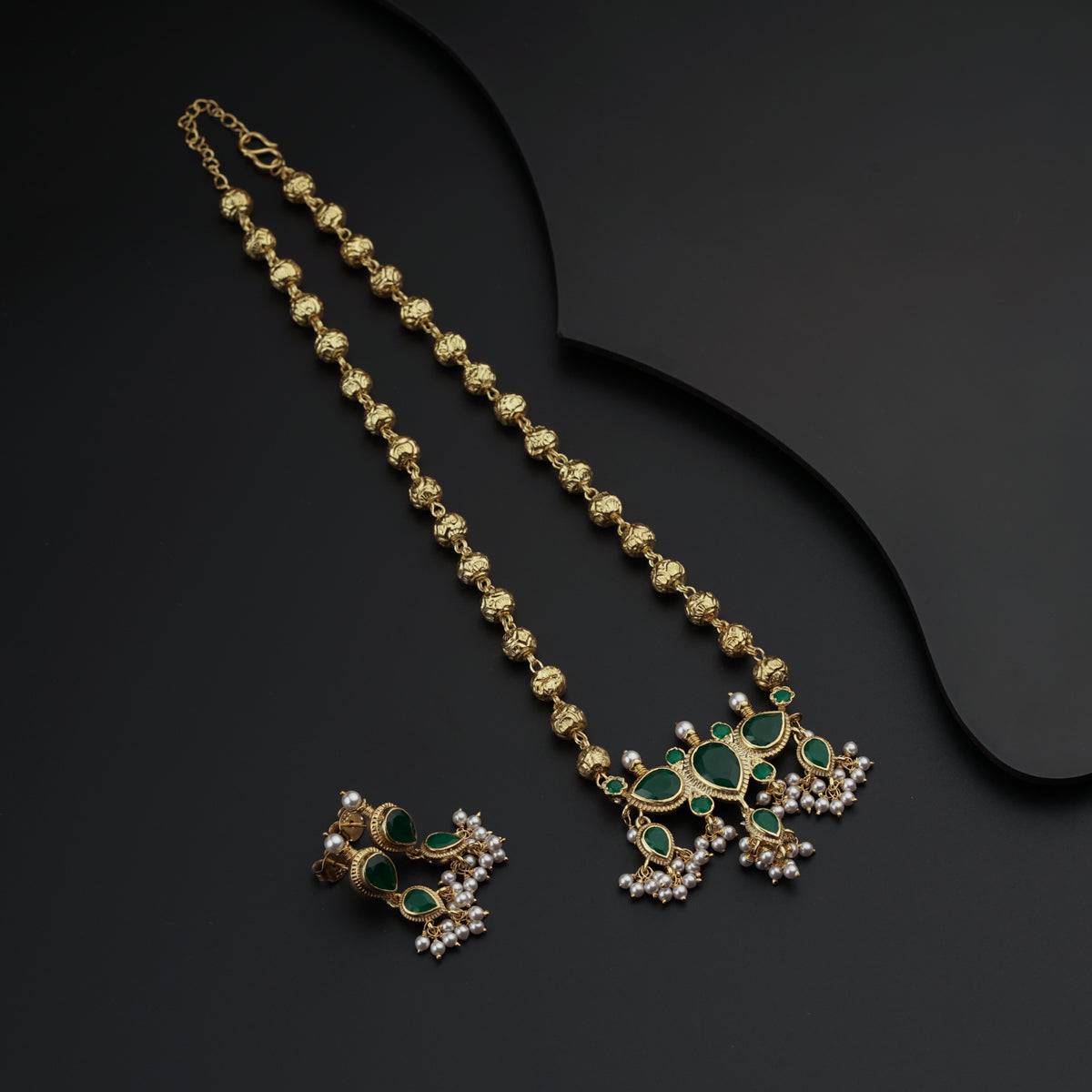 a pair of necklaces and earrings on a black surface