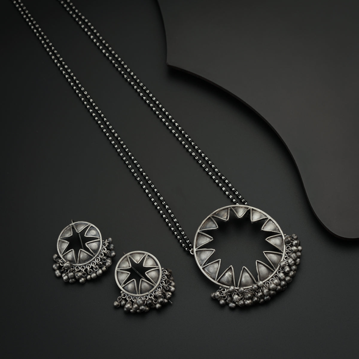 a pair of necklaces and a pendant on a black surface