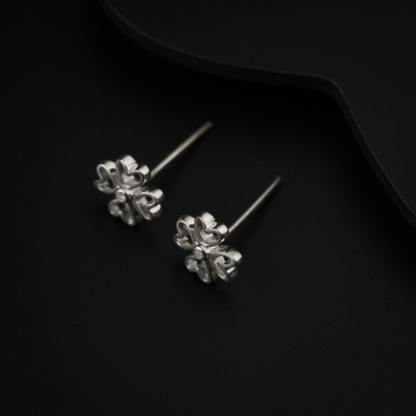 Silver flower-shaped earrings on black background