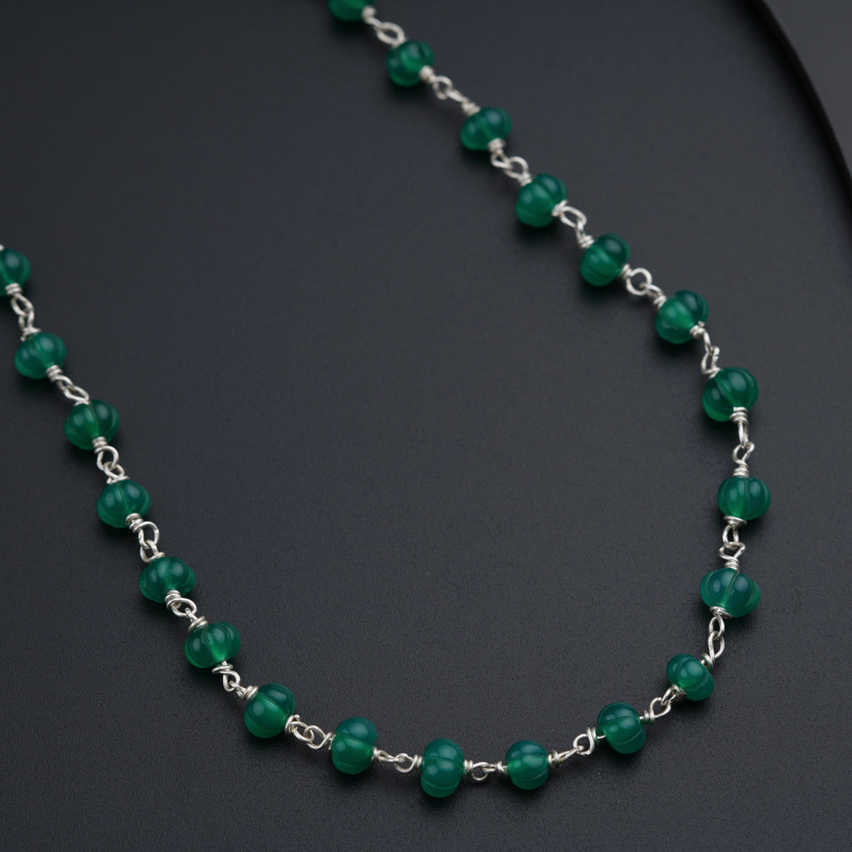 a green beaded necklace on a black surface