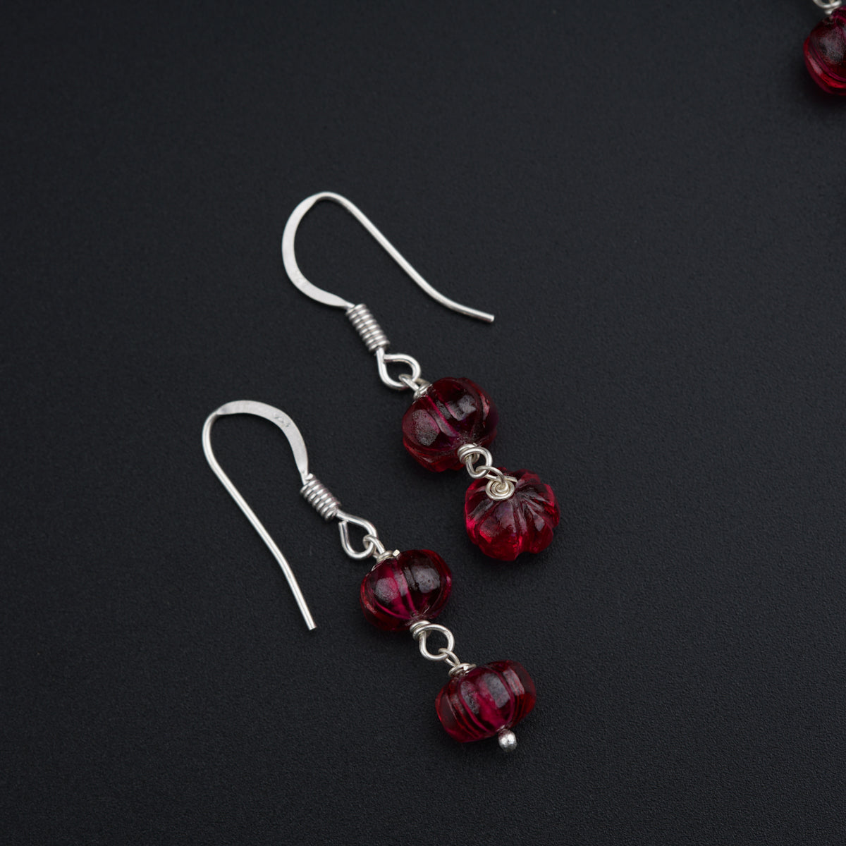 a pair of red glass beaded earrings on a black surface