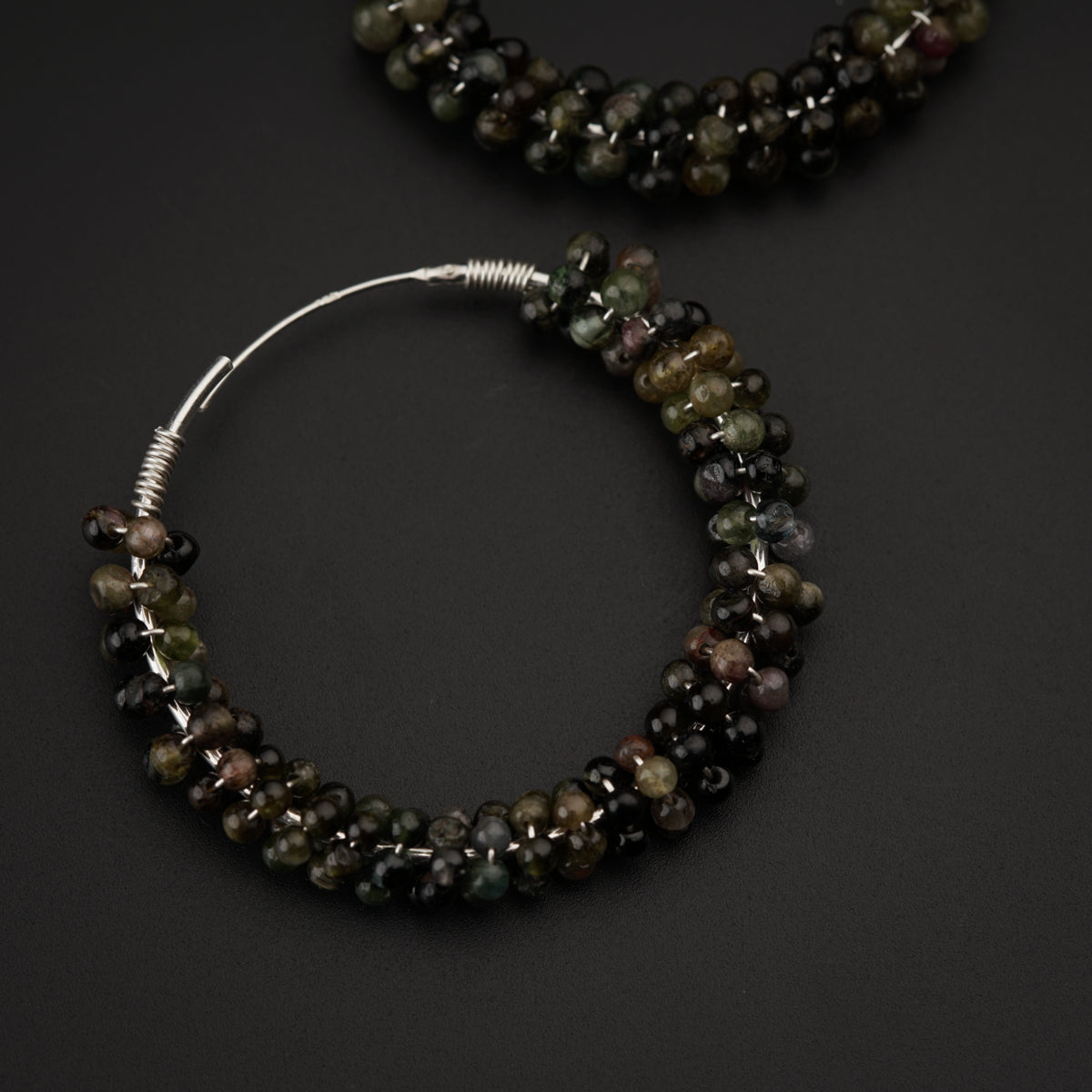 a pair of bracelets with beads on a black surface