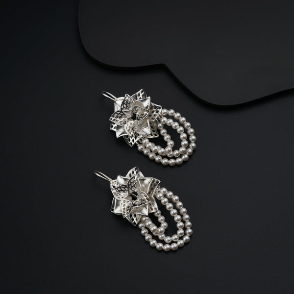 a pair of earrings with pearls on a black surface