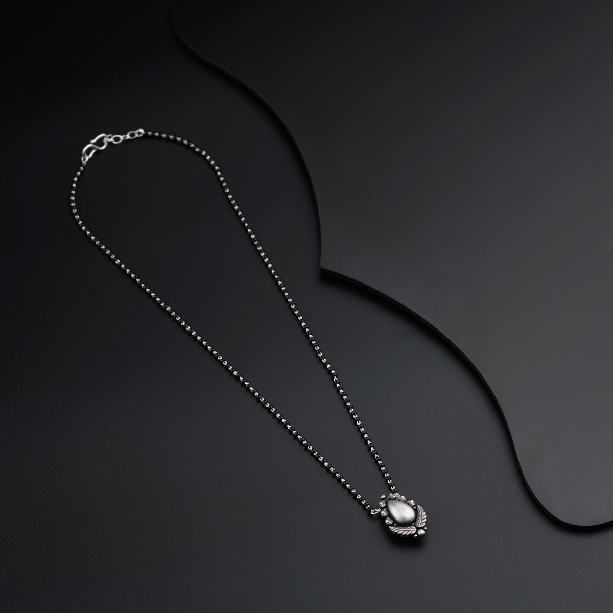 a necklace with a flower on a black background
