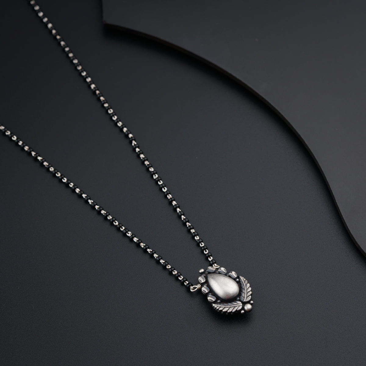a necklace with a shell on a black background