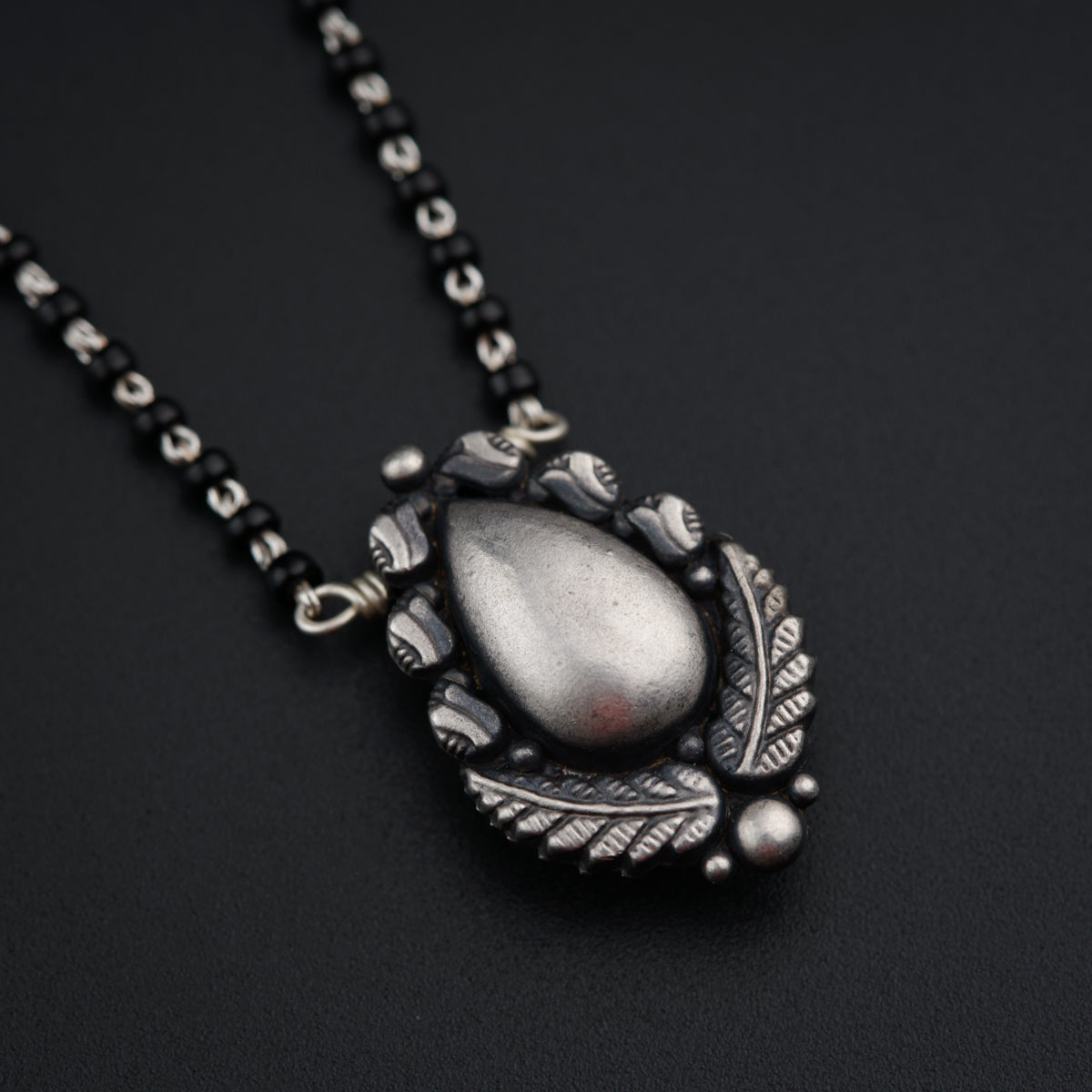 a necklace with a silver pendant on a black background
