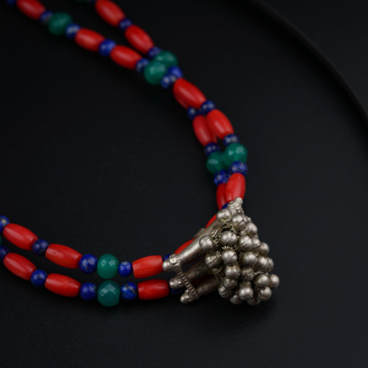 a red, blue, and green beaded necklace on a black surface