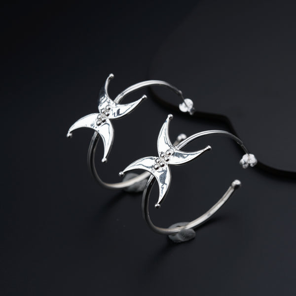 a pair of silver earrings on a black surface