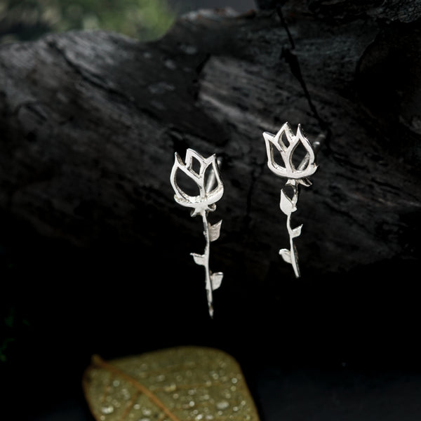 Silver lotus flower earrings on dark wood background