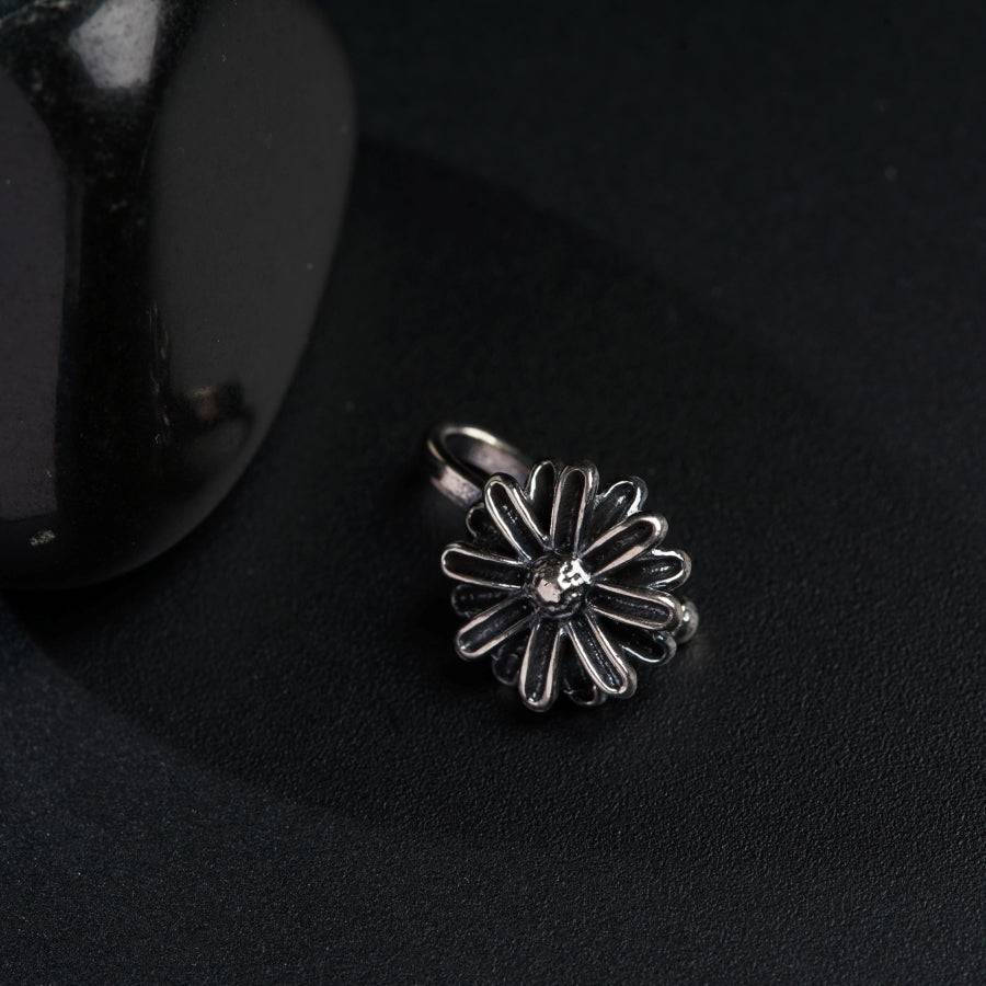 a ring with a flower on it sitting next to a black object