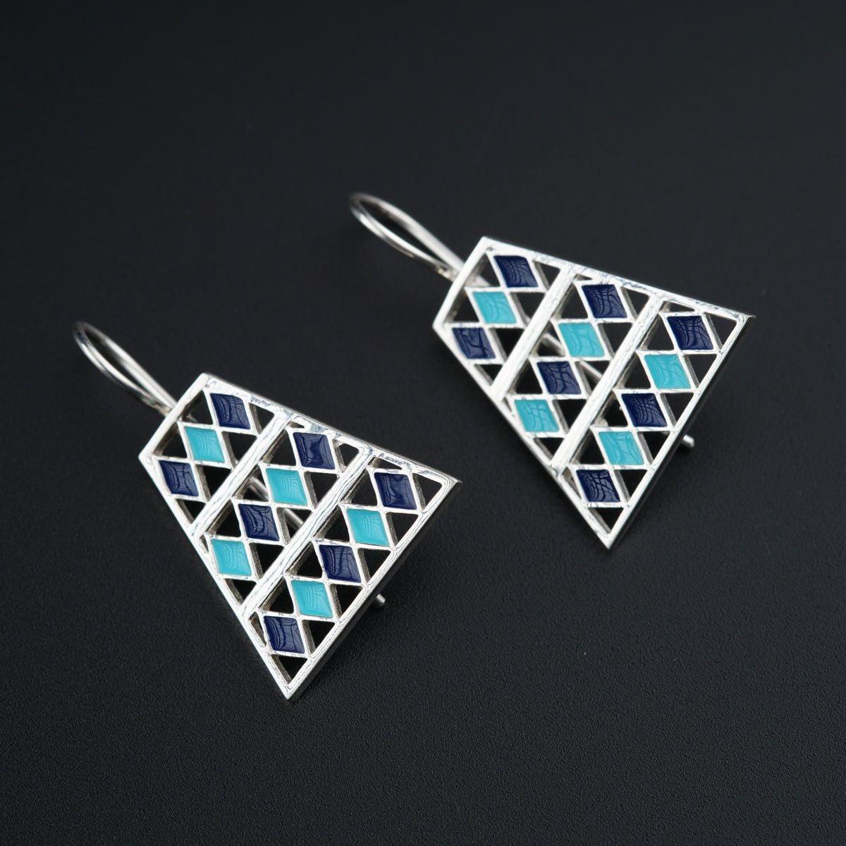 a pair of blue and white earrings on a black surface