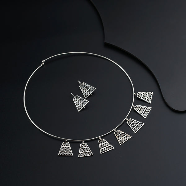 a silver necklace and a pair of earrings on a black surface