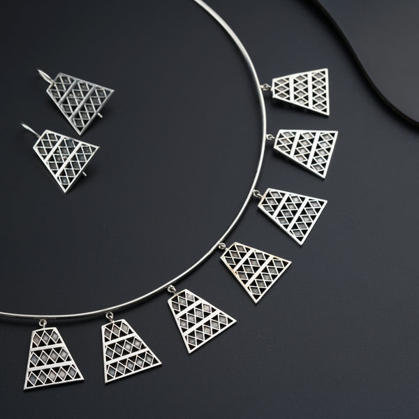 a silver necklace and matching earrings on a black surface