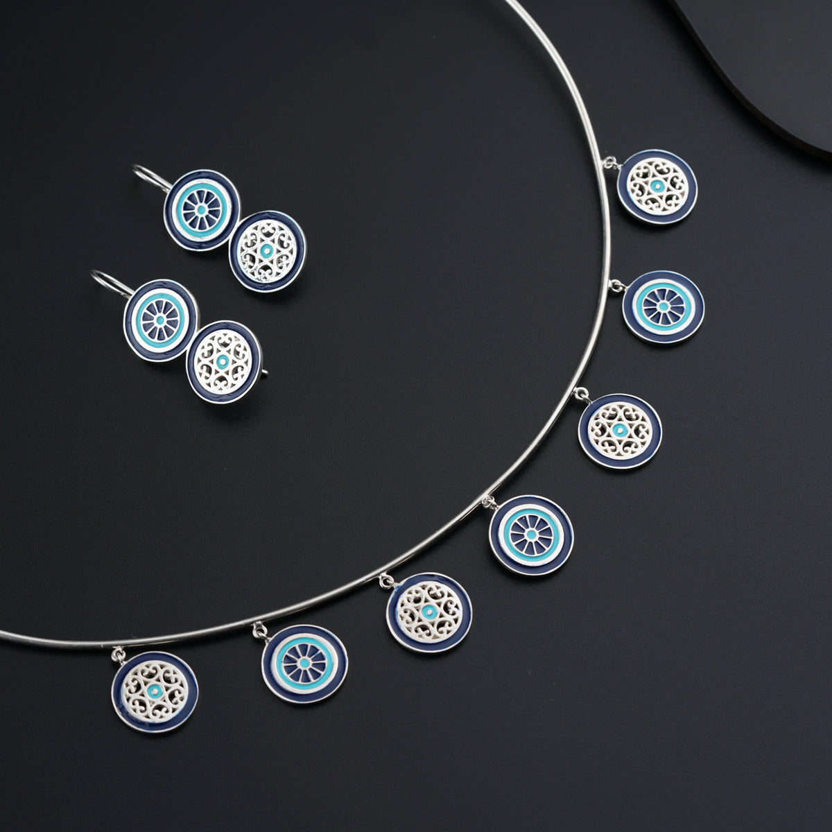 a blue and white necklace and earrings on a black surface