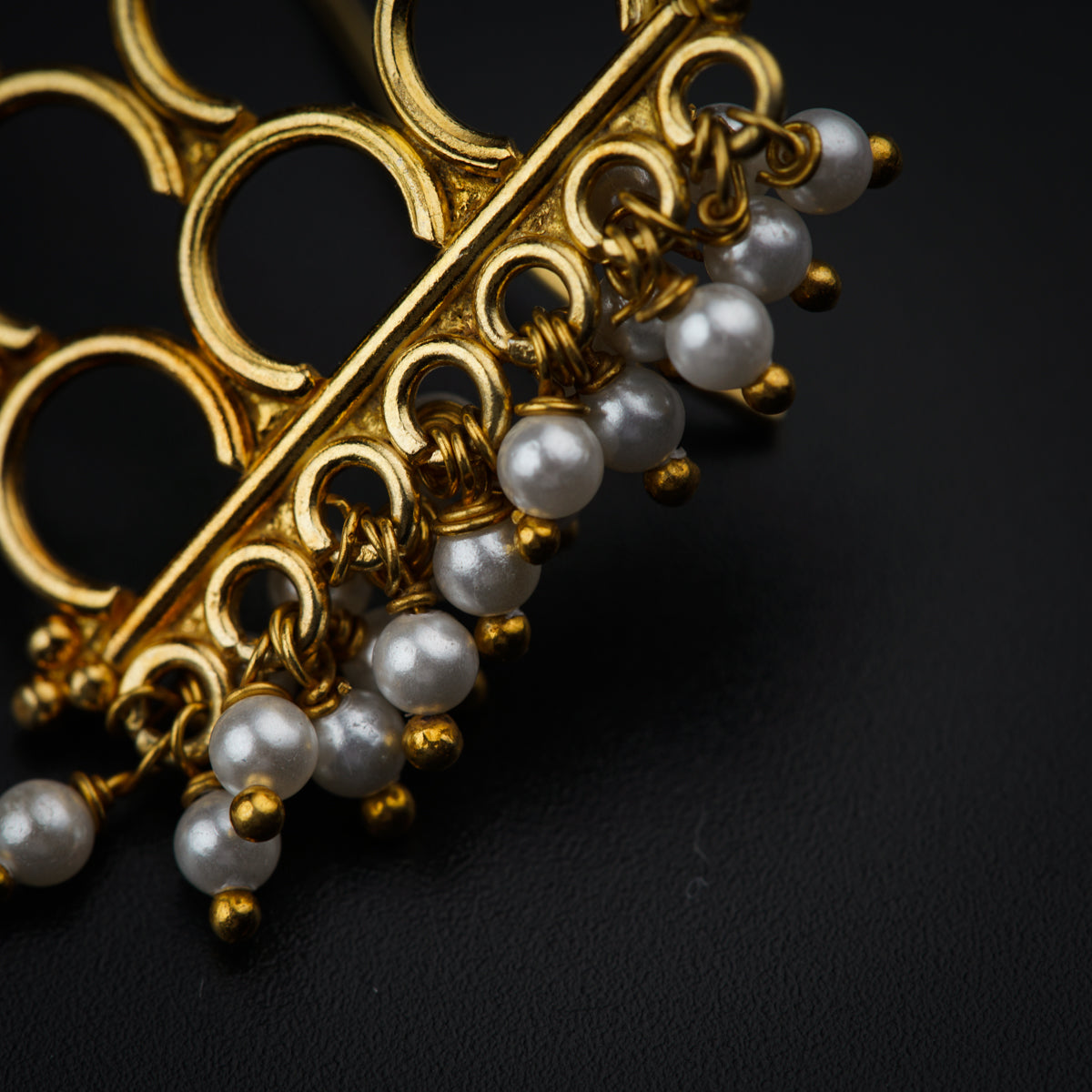 a close up of a gold brooch with pearls